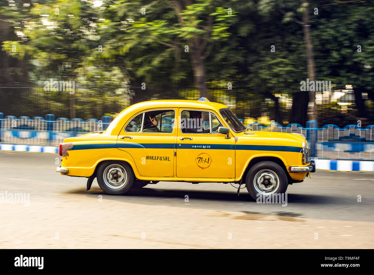 An Ambassador cab taxi with passengers on board is running on the streets of Kolkata. Stock Photo