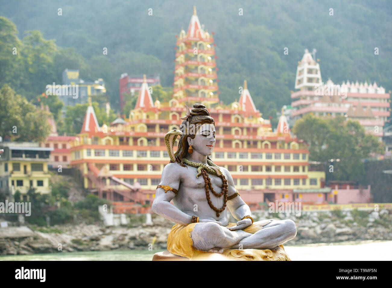 Stunning view of the statue of sitting Lord Shiva on the riverbank of the Ganges river. Blurred Trimbakeshwar Temple in the background. Stock Photo
