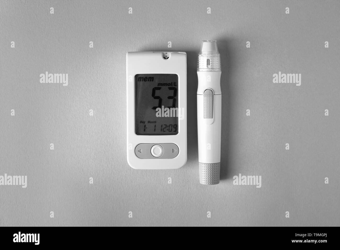 Digital glucometer with lancet pen on grey background. Diabetes control Stock Photo