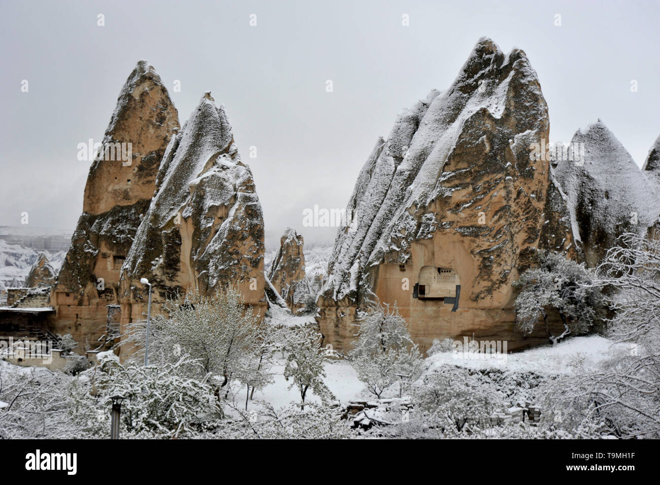 Unusual natural stone formations with snow in Goreme in the Cappadocia region of Turkey Stock Photo