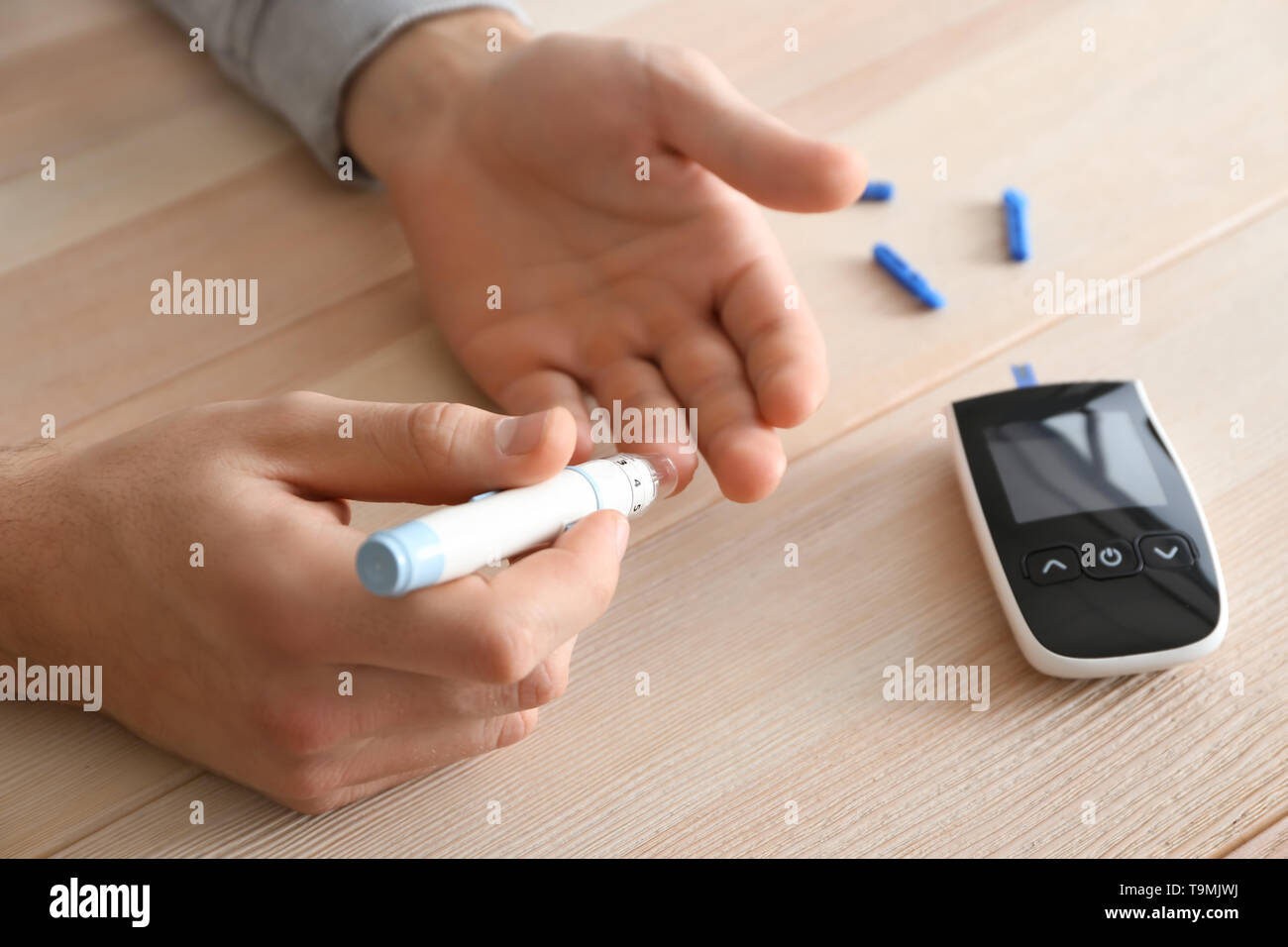 Man taking blood sample with lancet pen, closeup. Diabetes control