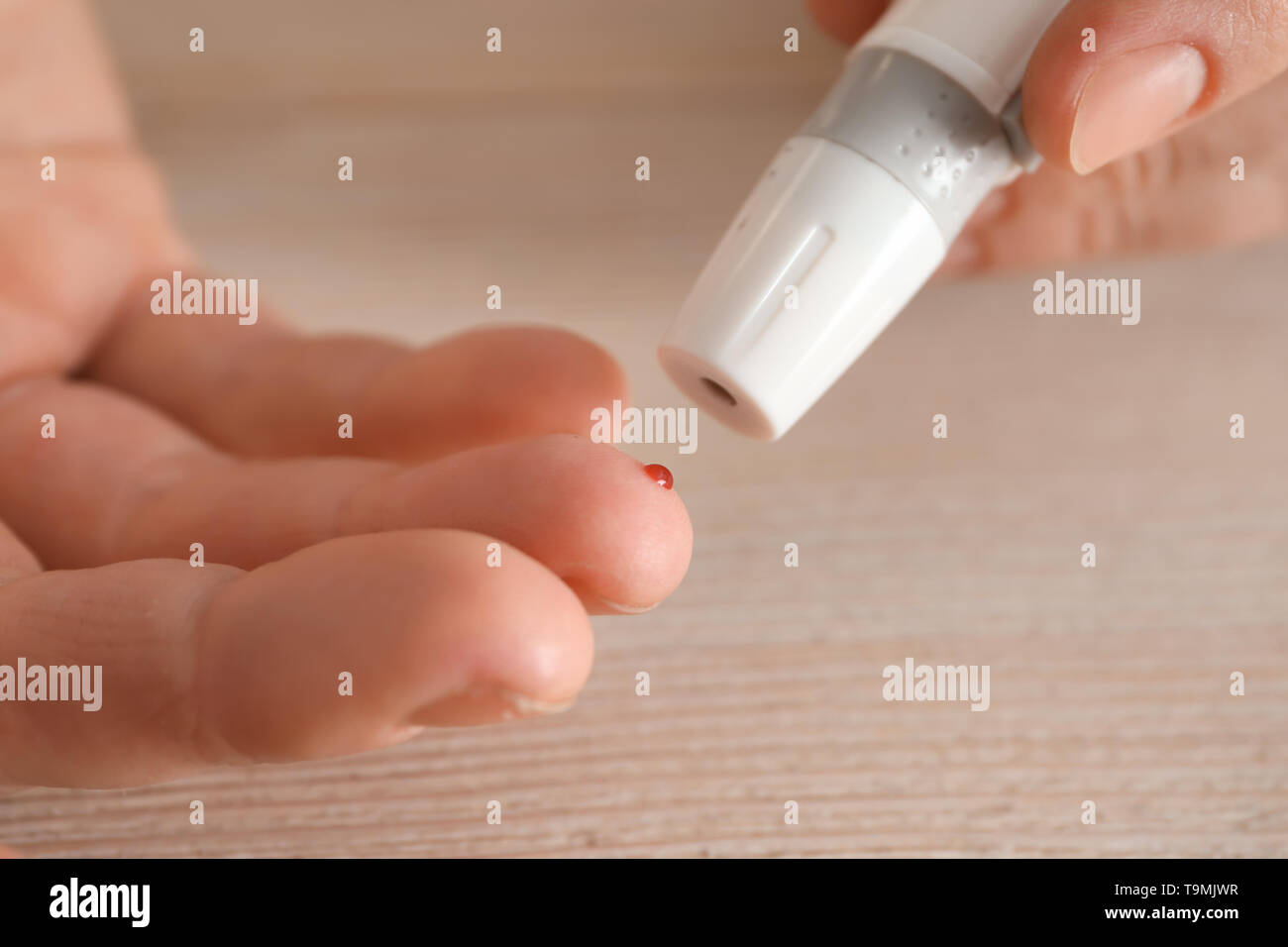 Woman taking blood sample with lancet pen, closeup. Diabetes control