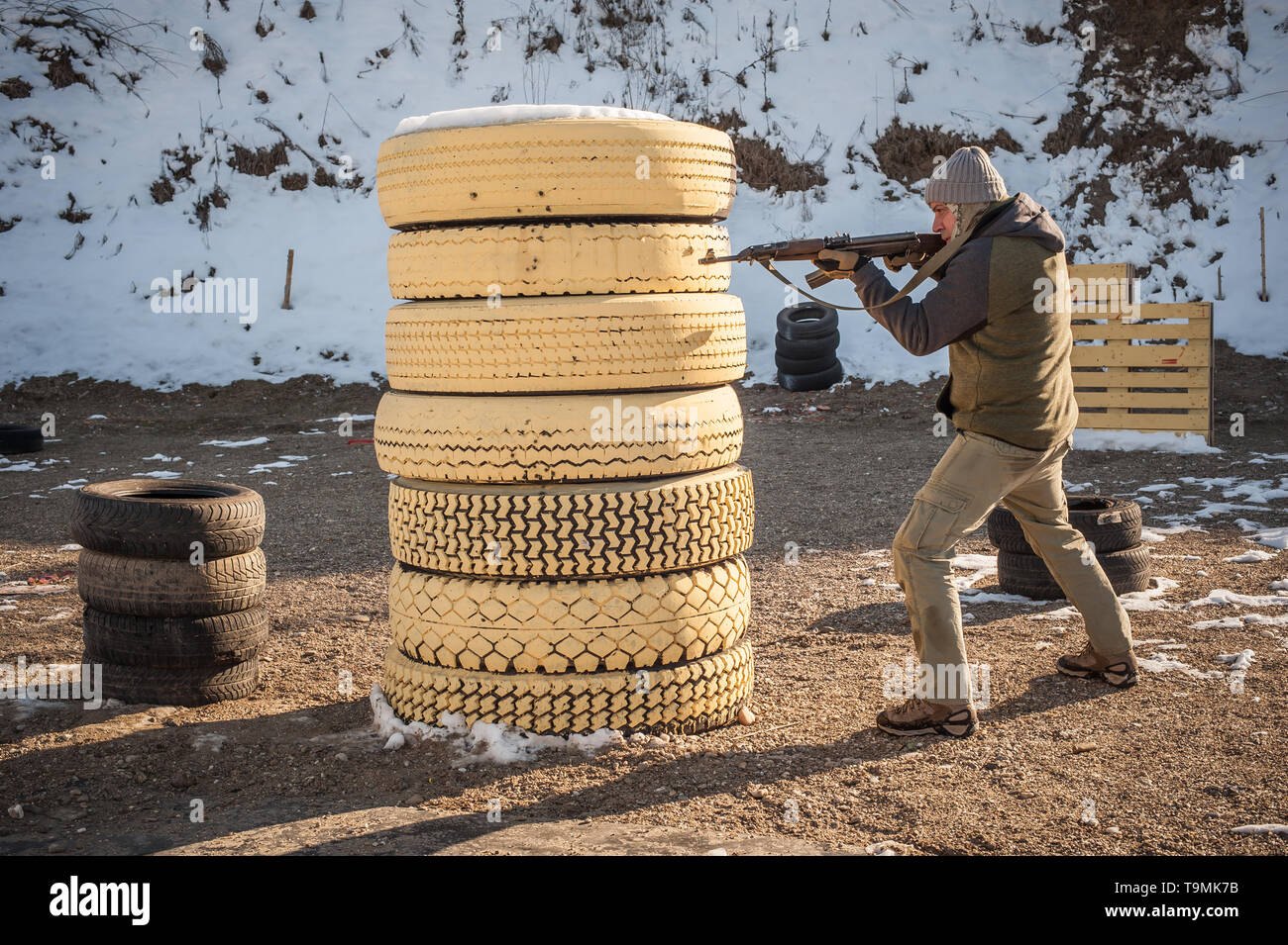 Instructor demonstrate body position of combat rifle shooting at winter
