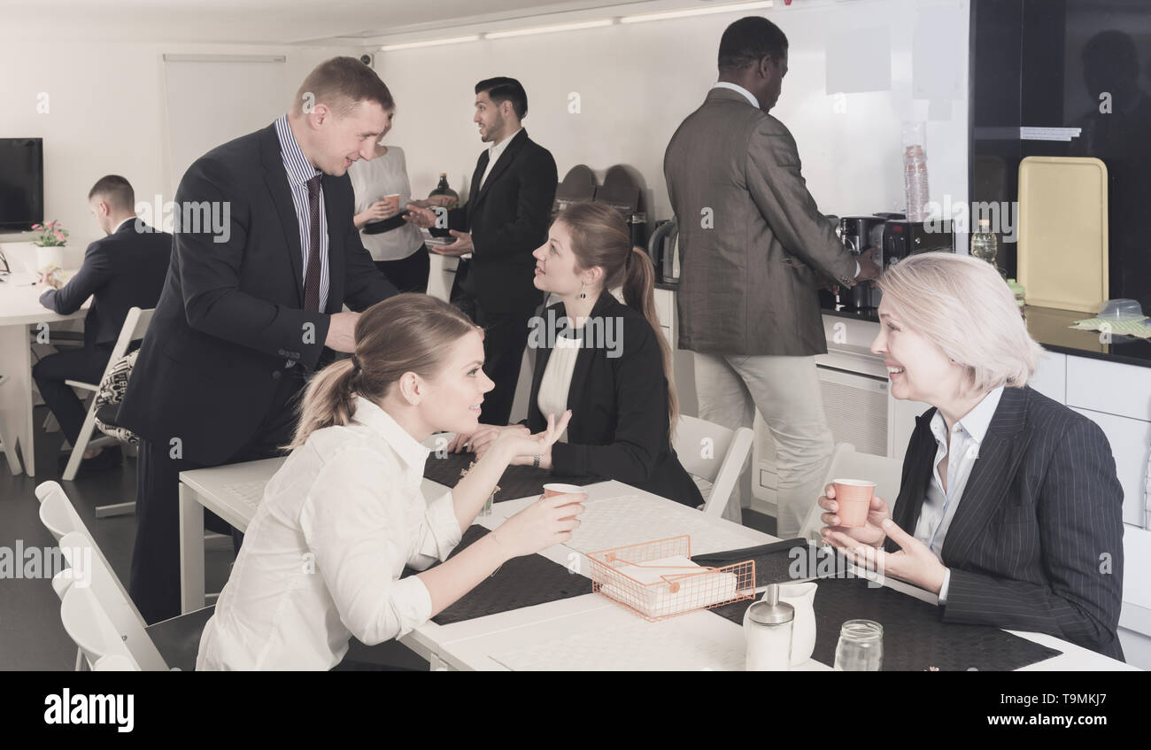 Cheerful multinational colleagues having break at office, drinking coffee and talking Stock Photo