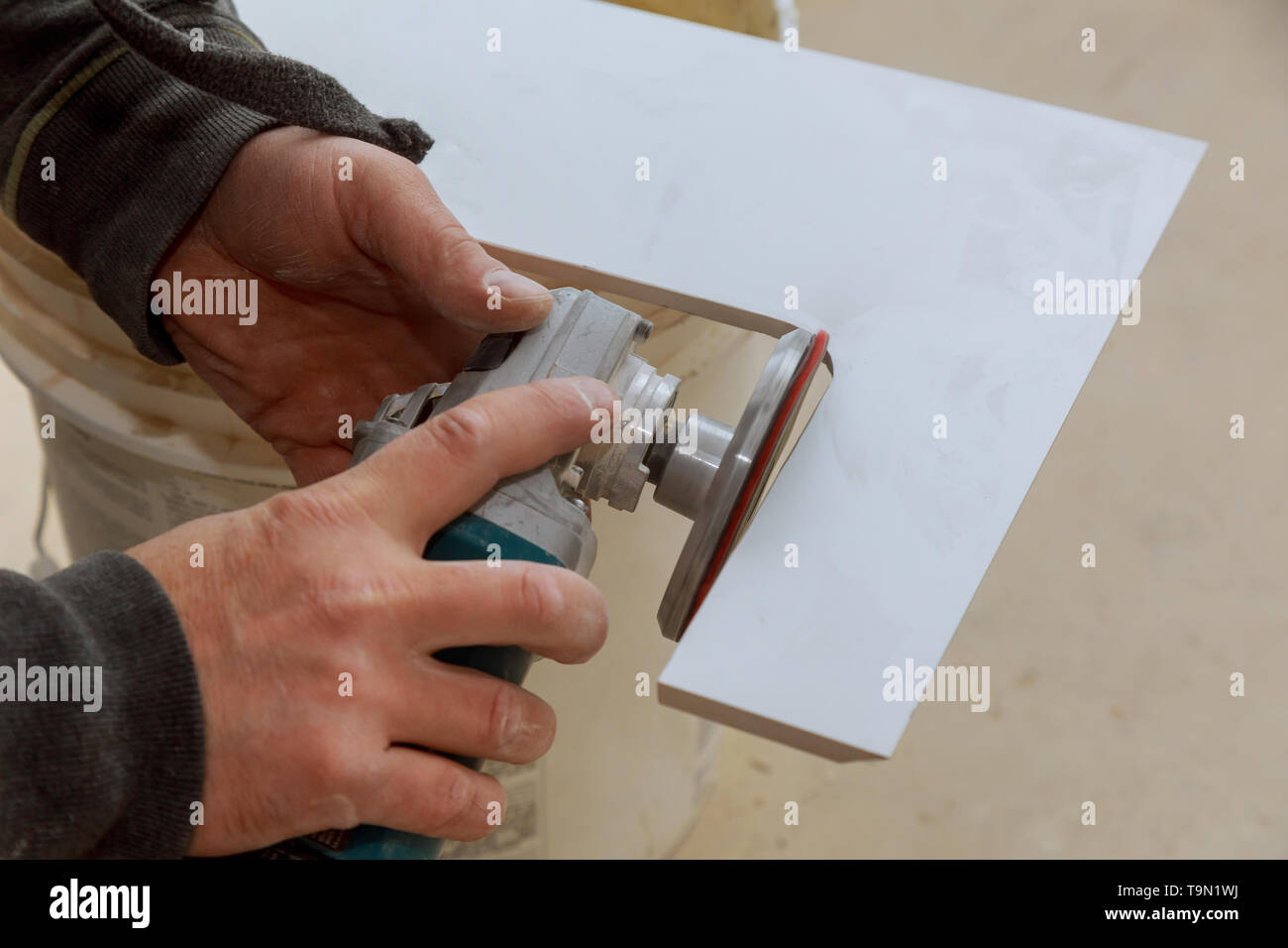 Worker cutting flooring tile with an diamond electric saw blade a