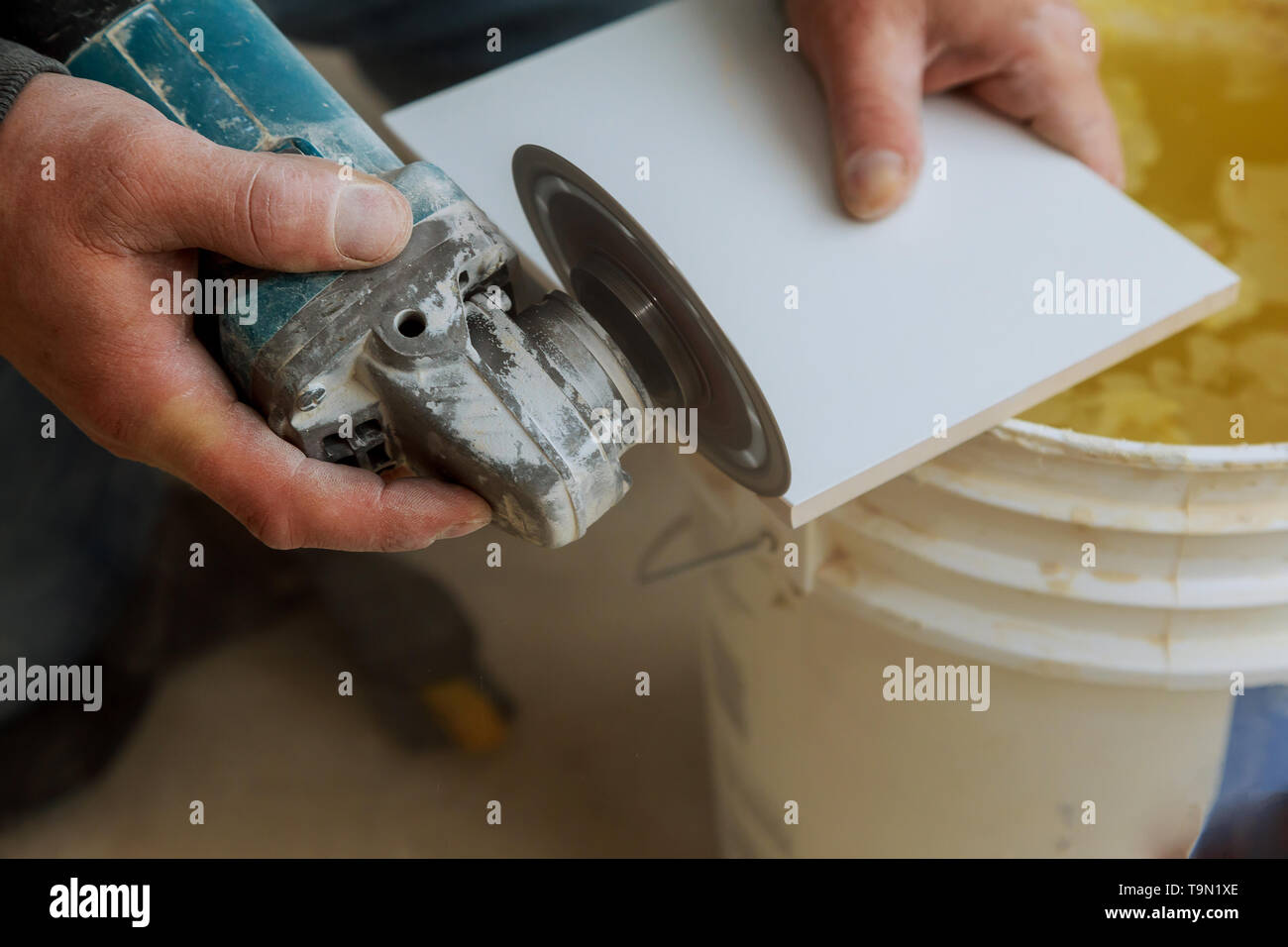Worker cutting a tile using grinder cut into layers of ceramic floor