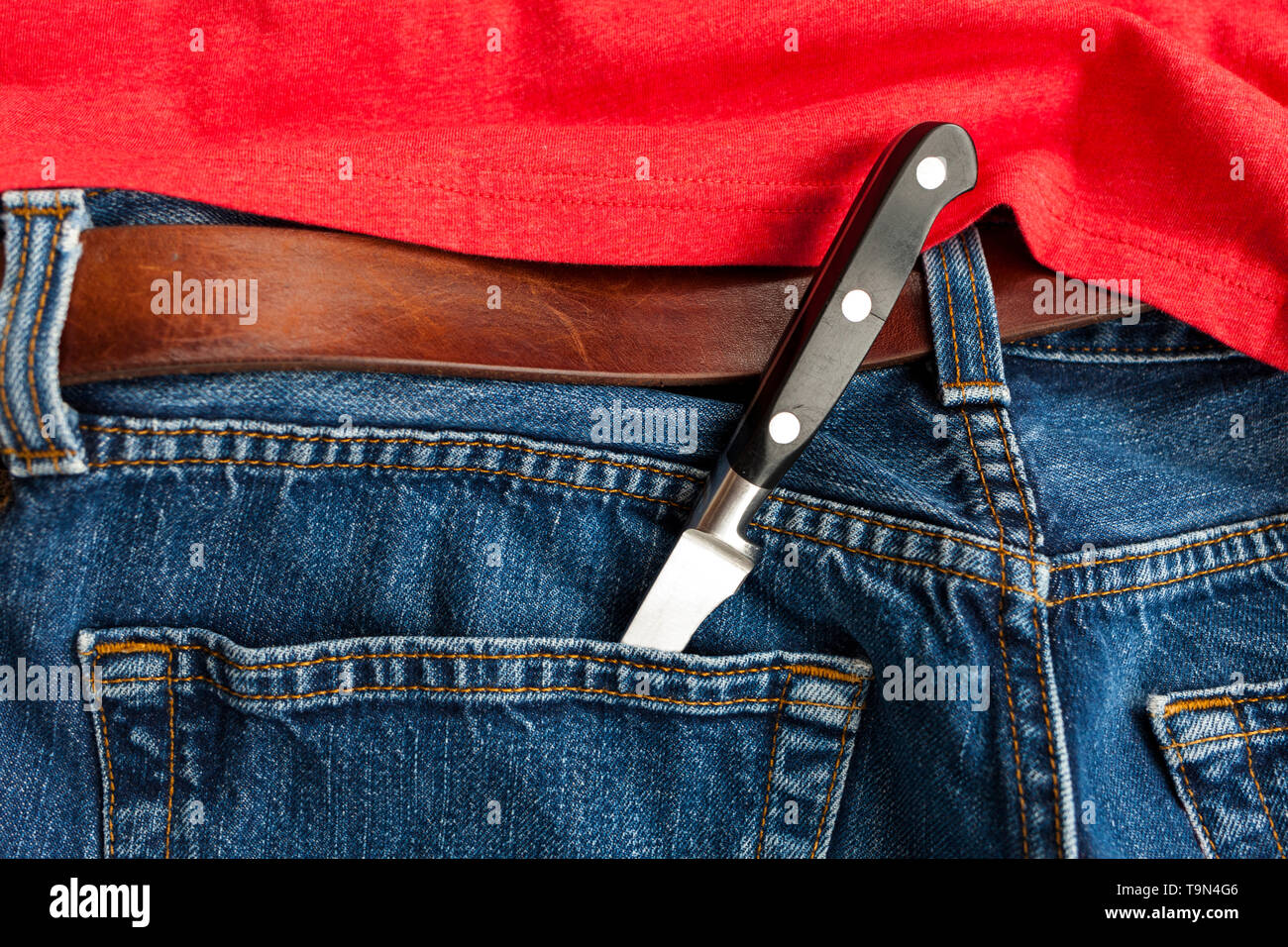 Knife crime. A knife in the back pocket of denim jeans. Stock Photo