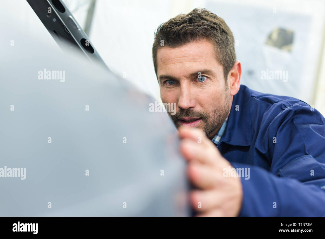 industrial automotive body worker inspecting the surface Stock Photo