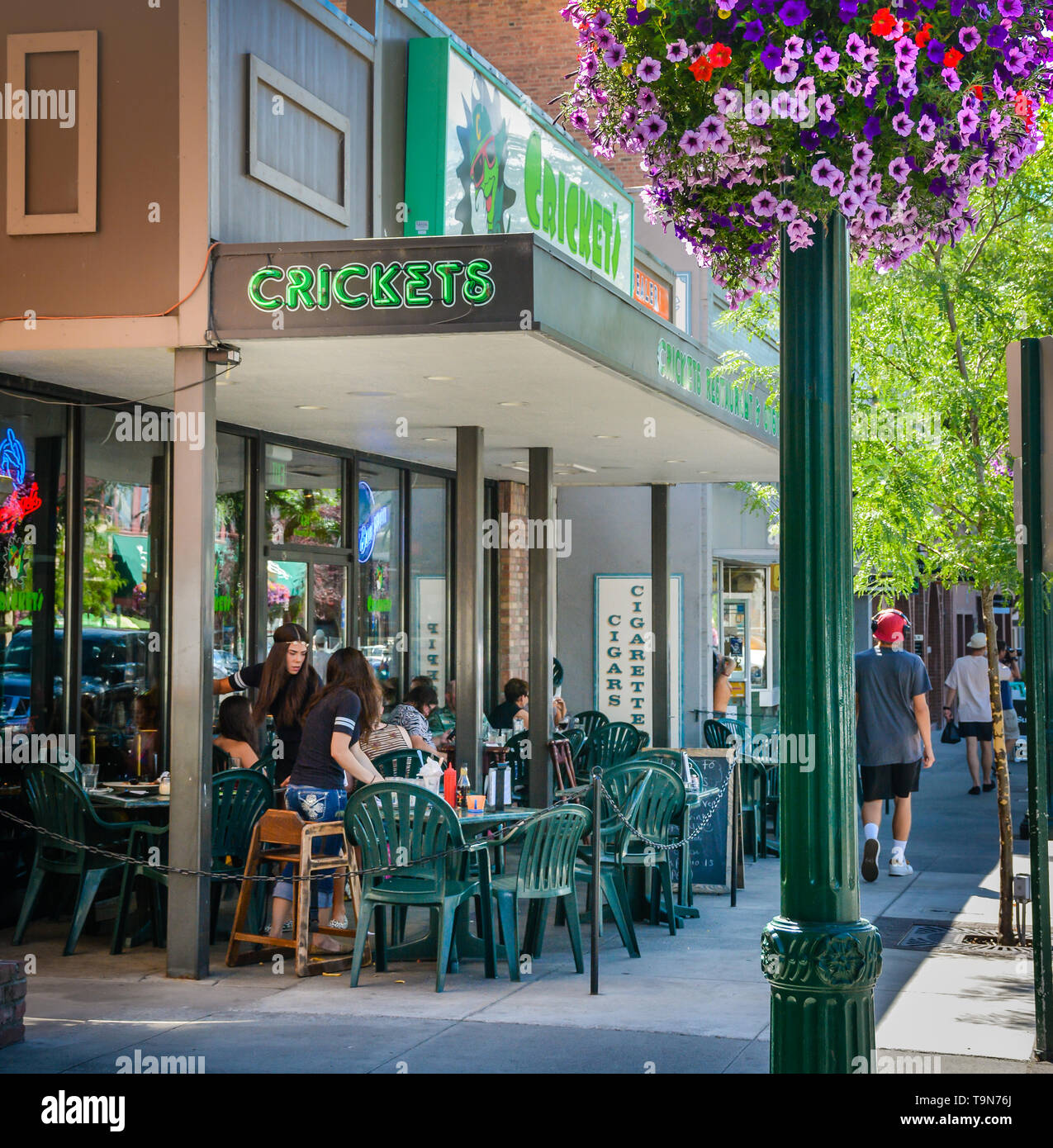 The patio at Cricket's Bar with outdoor dining reflects the relaxed colorful summer vibe with tourists enjoying downtown Coeur d'Alene, ID Stock Photo