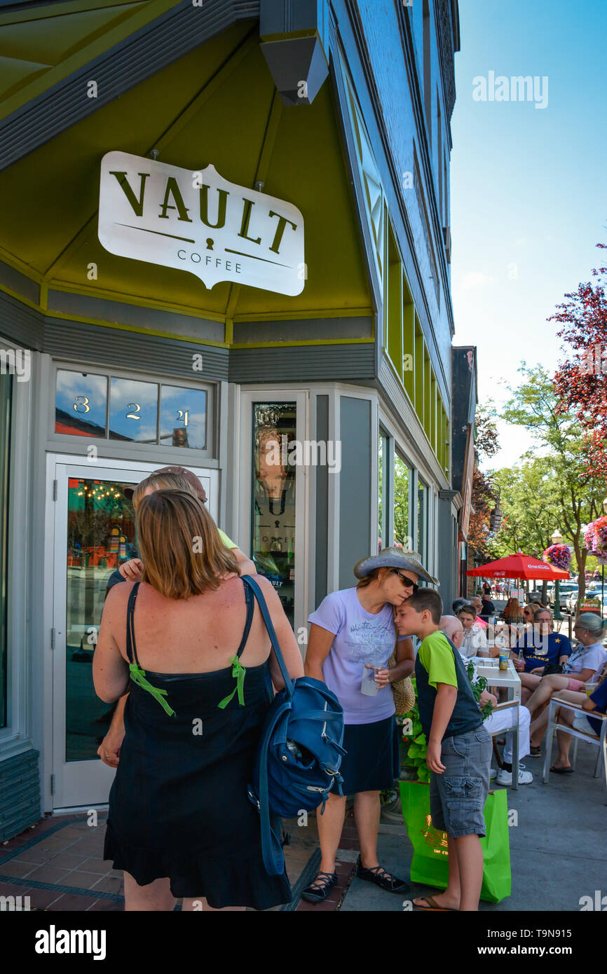 Affectionate Mom and son wait outside a busy coffee house in Coeur d'Alene, ID Stock Photo