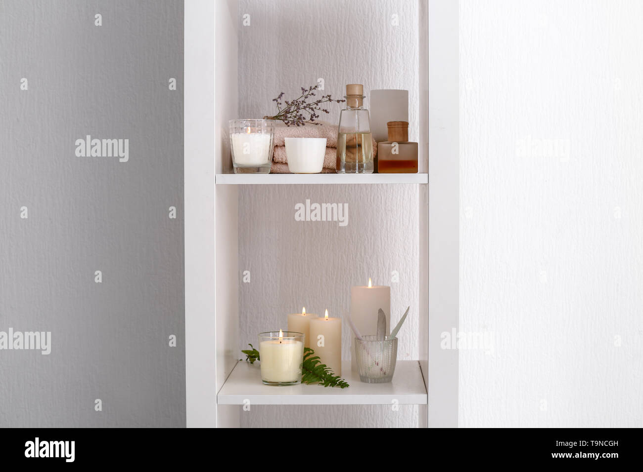 Many burning candles on shelves near white wall Stock Photo Alamy
