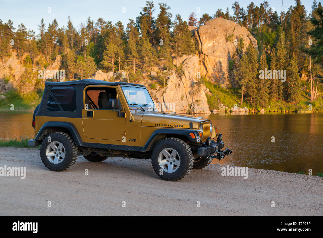 BLACK HILLS, SOUTH DAKOTA - June12, 2014: A 2003 Inca gold Jeep Rubicon  parked next to a lake with the late afternoon sun hitting the rocks of the  Stock Photo - Alamy