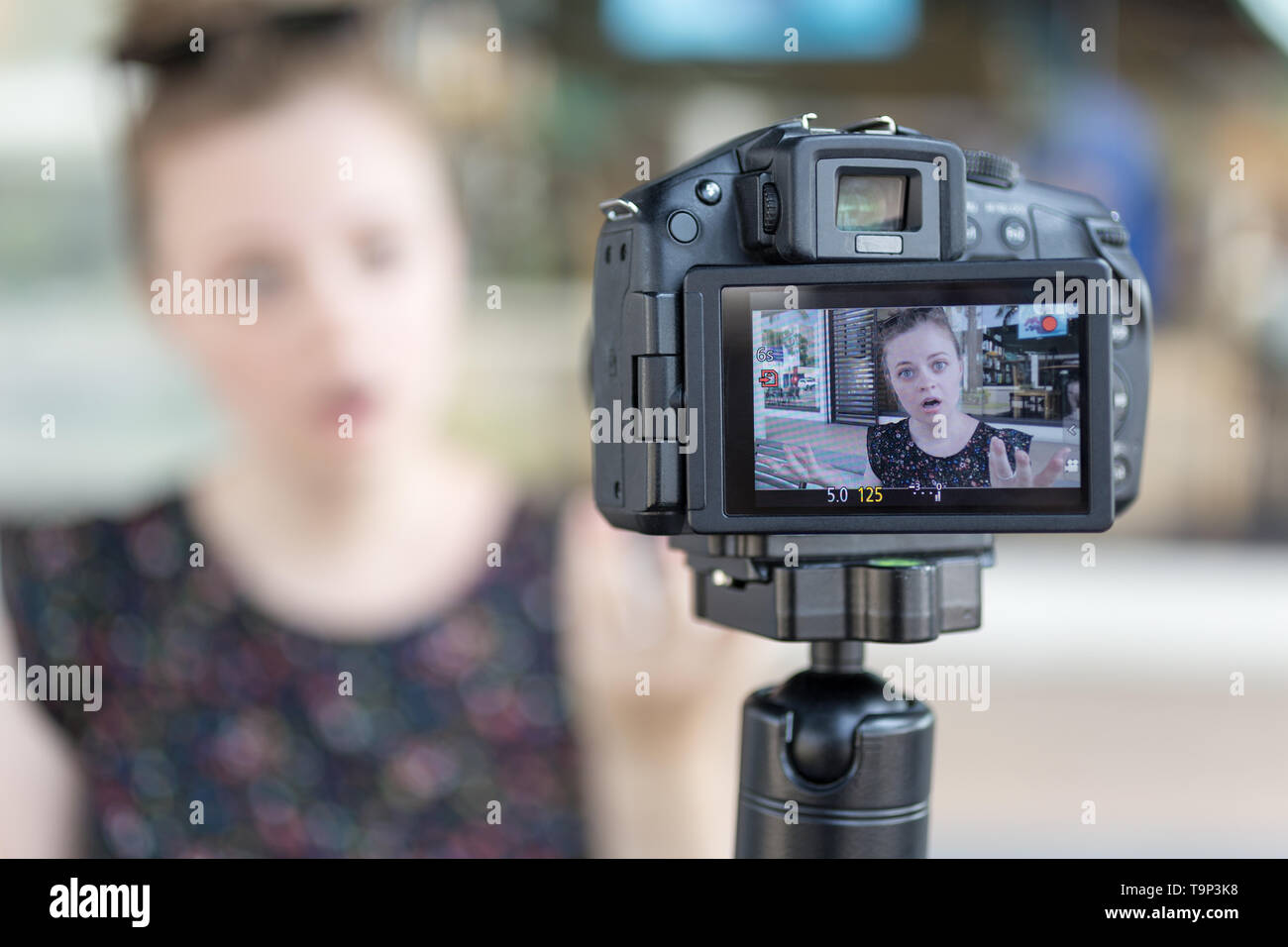A caucasian young girl making a video blog (vlog) behind the camera Stock Photo