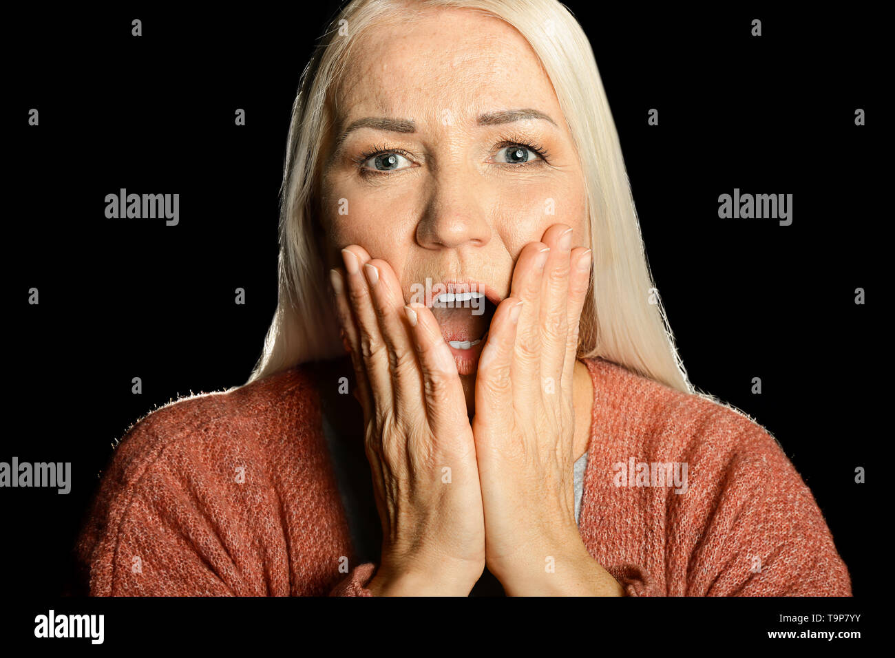 Portrait of screaming mature woman on dark background Stock Photo