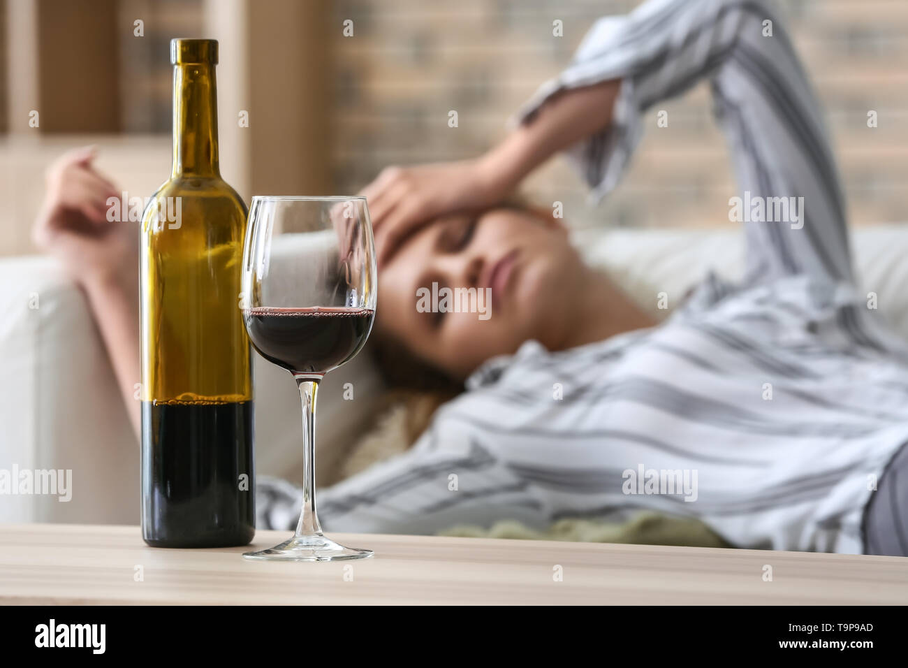 Glass and bottle of wine on table of drunk woman Stock Photo Alamy