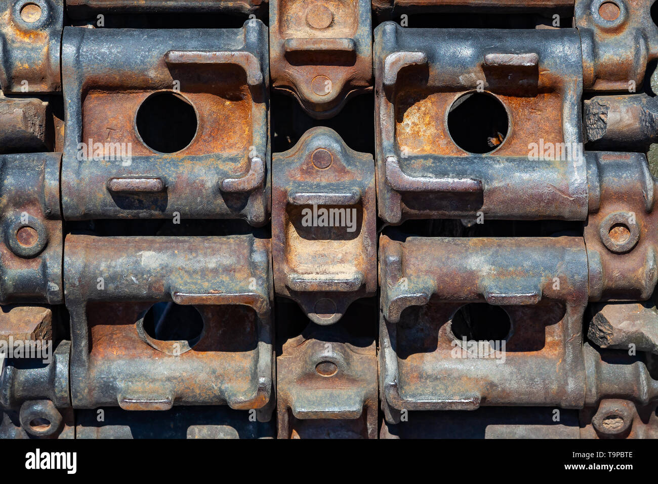Background Close-up on a rusty old caterpillar of green tank worn on wheels standing on the road. Military equipment for the murder and the achievemen Stock Photo