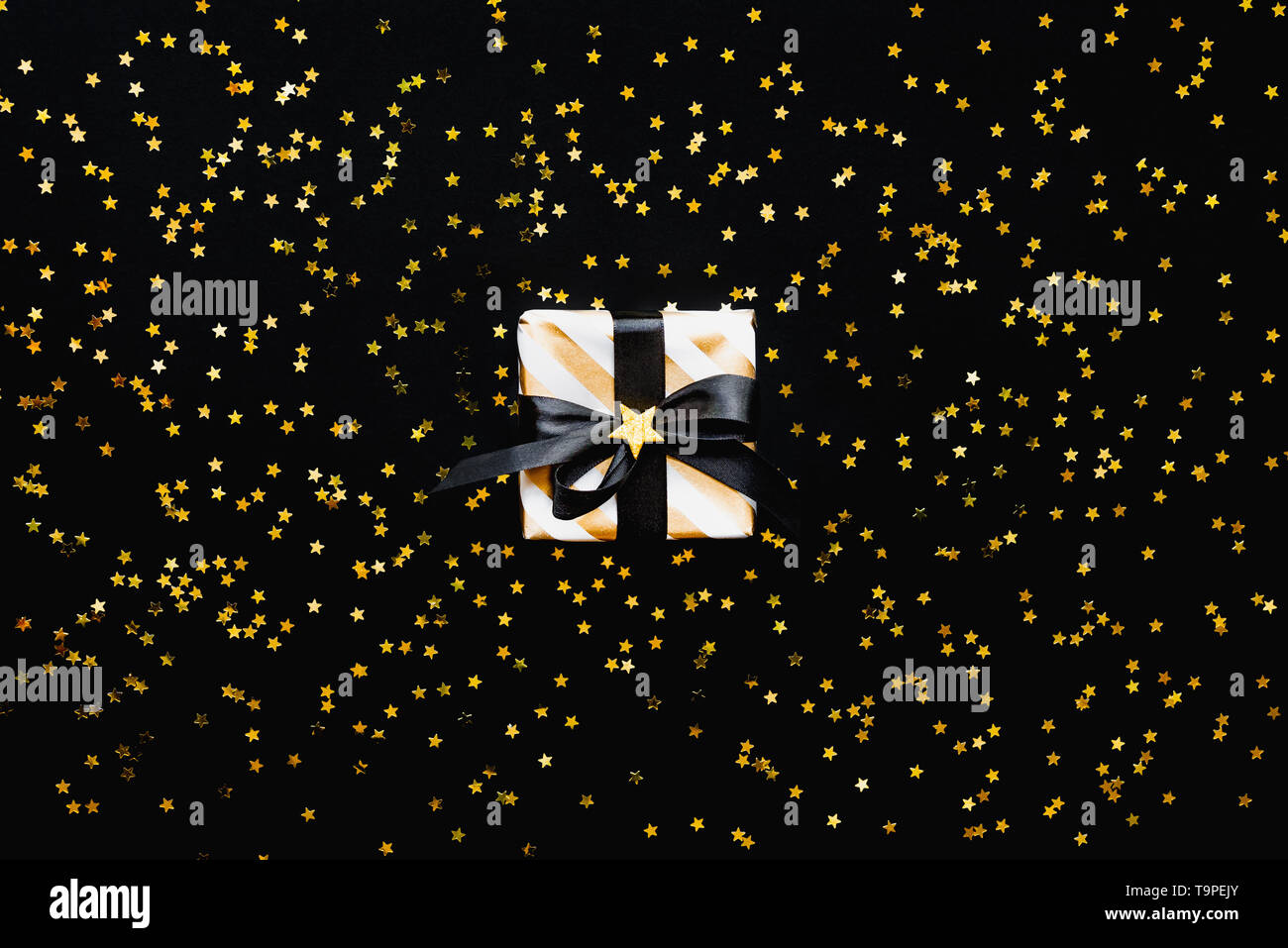 Star shaped golden sequins on a black background. Stock Photo