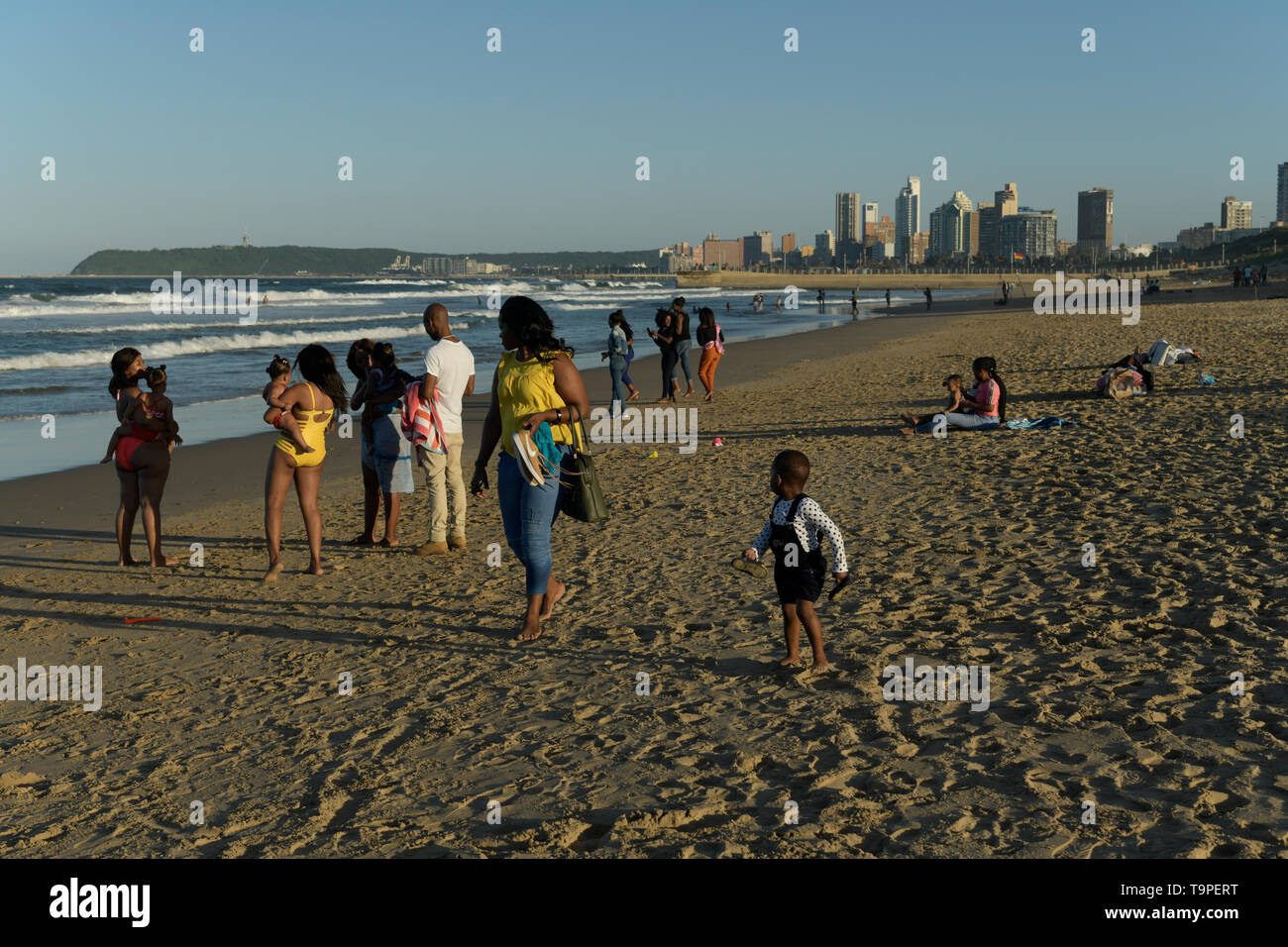 Family groups walking and standing on beach, Durban, KwaZulu-Natal, South Africa, ethnic, landscape, people, friends, city, buildings Stock Photo