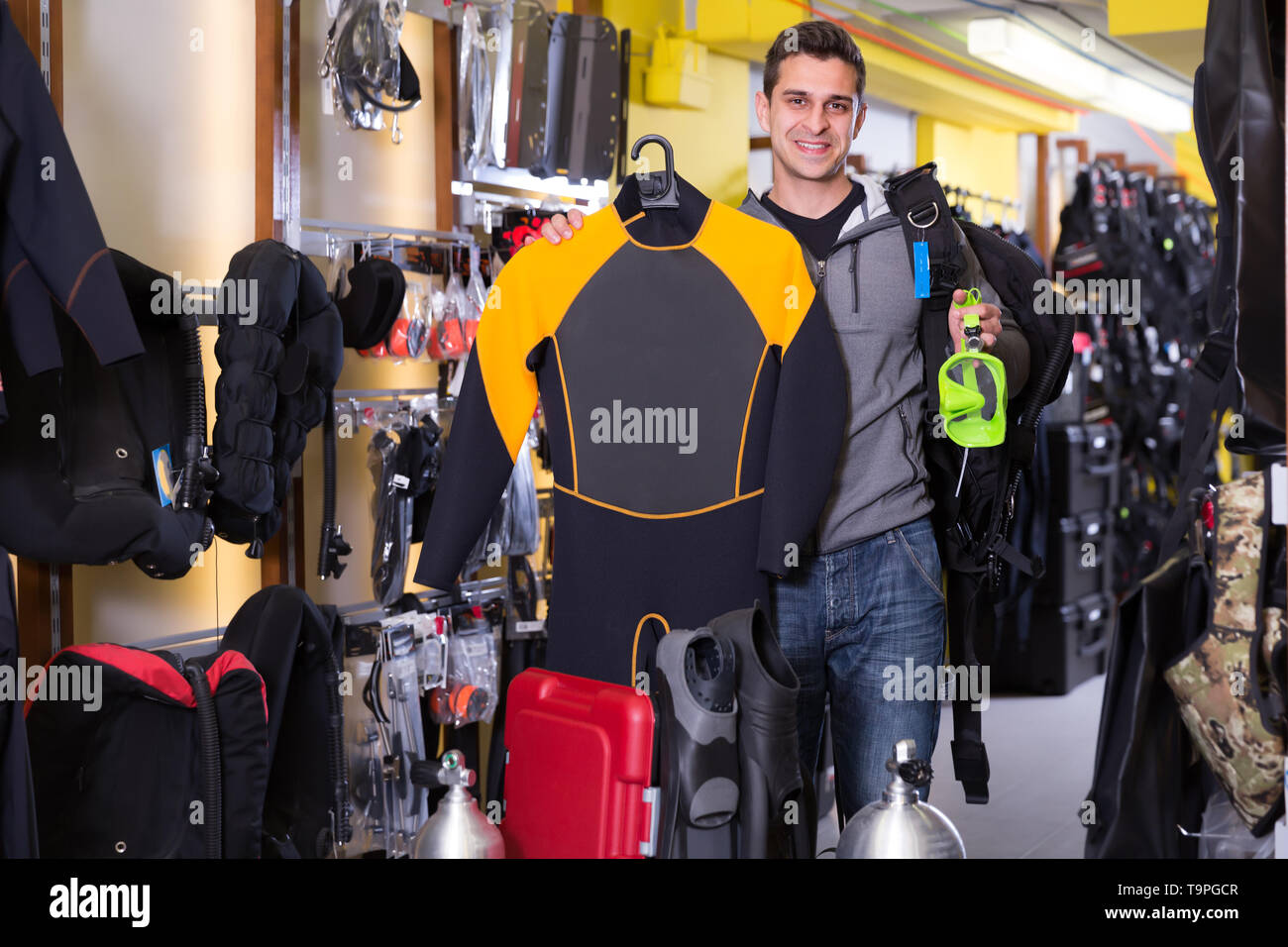 Sporty man is satisfied of full set of diving equipment in the store