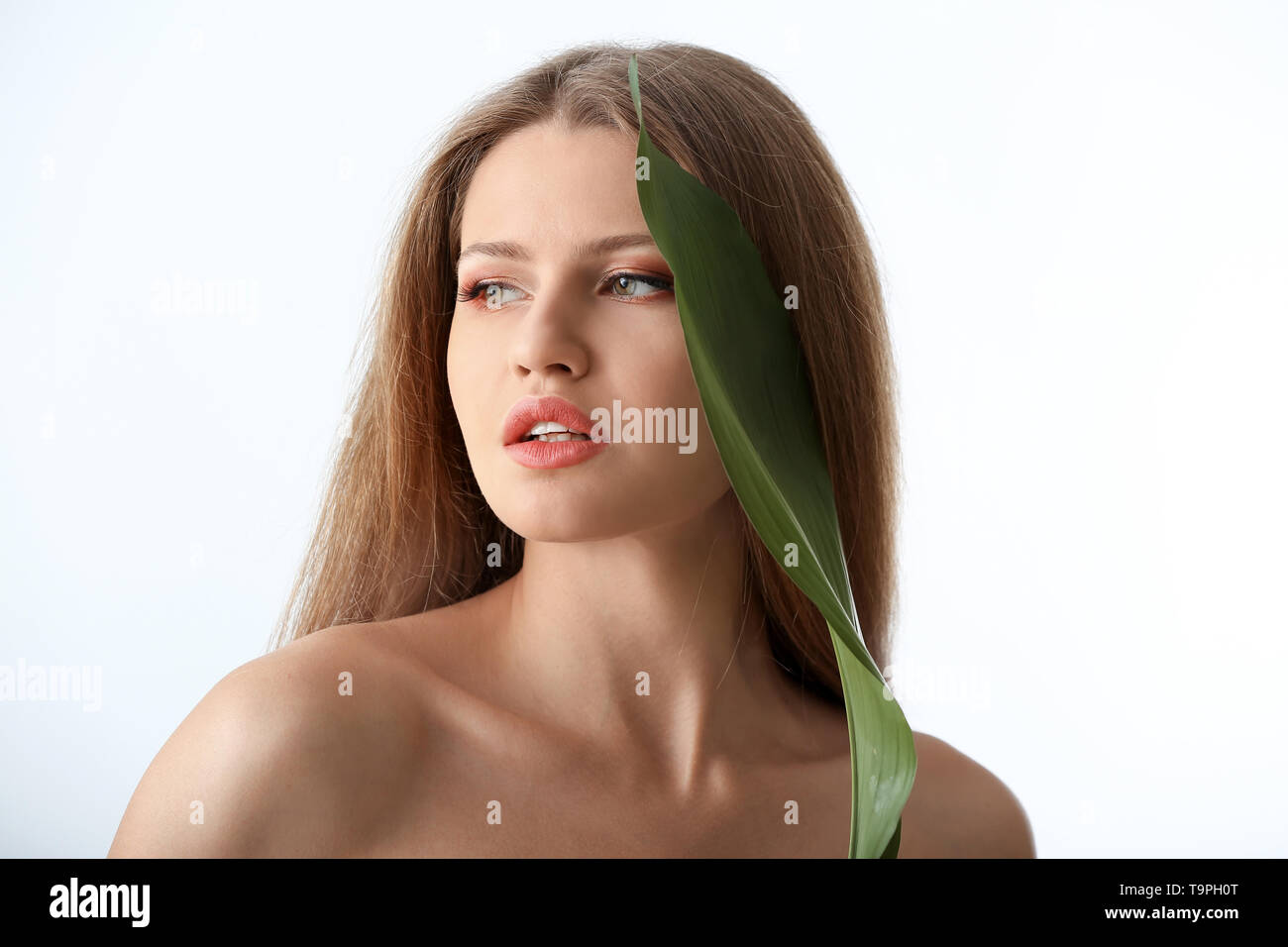 Portrait of beautiful woman with green tropical leaf on white ...