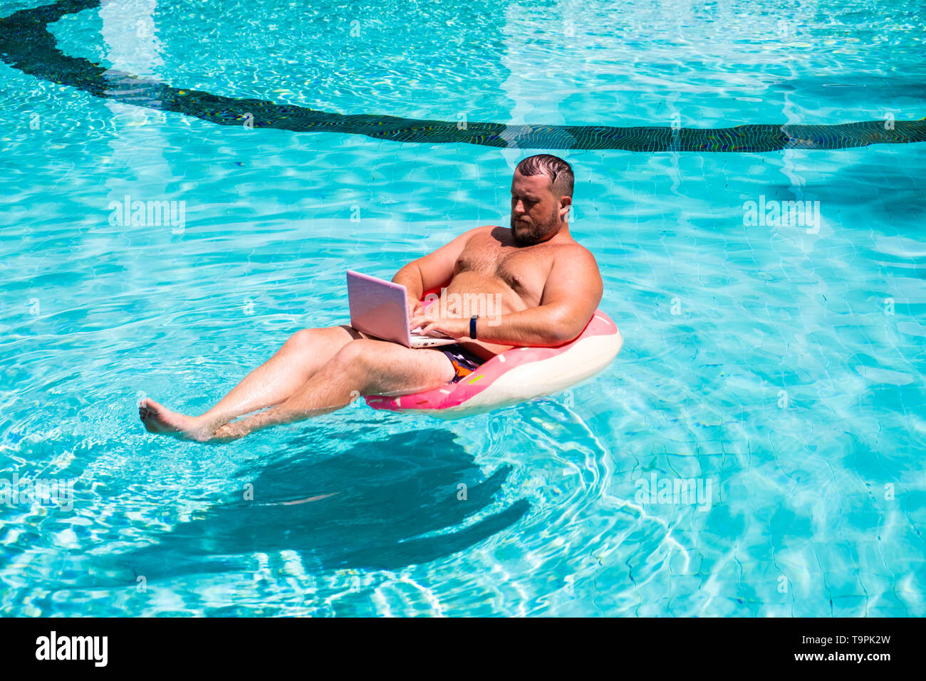 Freelancer with an inflatable ring in the water in the pool works on the  computer. Funny Fat Man in Swimming Circle with Pink Laptop. freelance  Stock Photo - Alamy