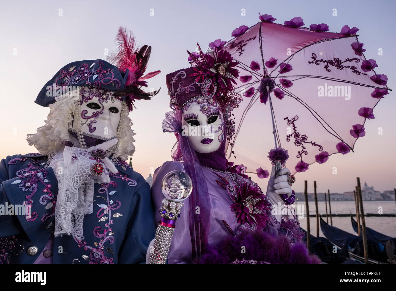 Portraits of a masked couple in beautiful creative costumes, posing at Grand Canal, Canal Grande, celebrating the Venetian Carnival Stock Photo