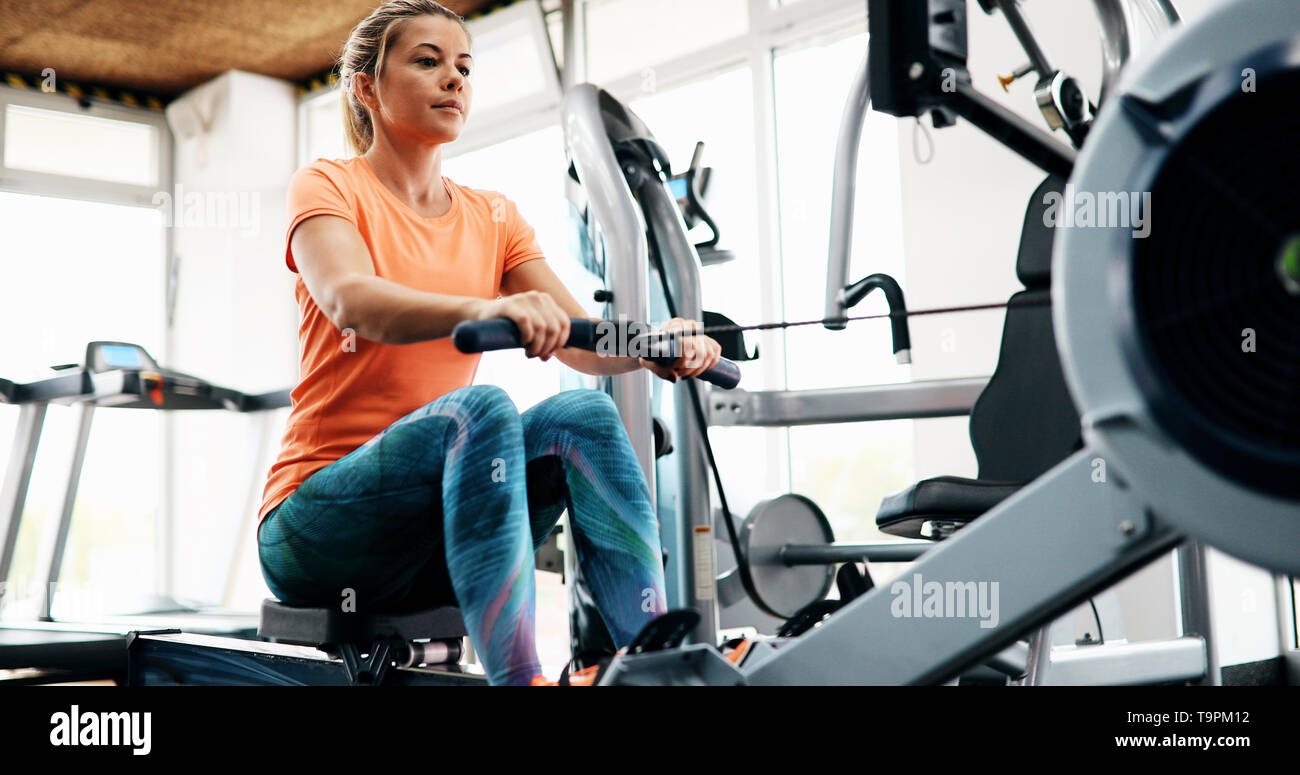 Woman pulling on row machine in fitness Stock Photo