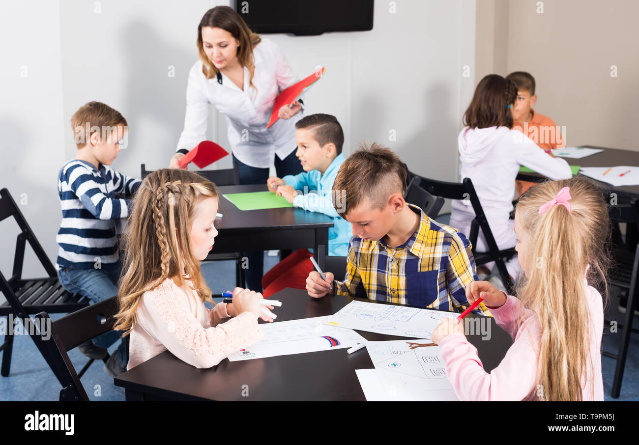concentrated little children with teacher drawing in classroom on the ...