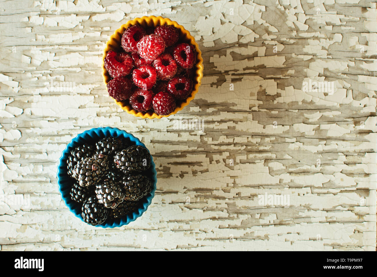 Raspberries and Blackberries in Ceramic Bowls on Rustic Wooden Background Stock Photo