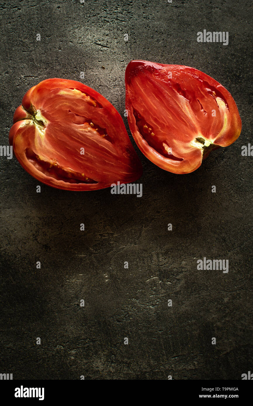 Halved Organic Red Bull's Heart Heirloom Tomato on Rustic Dark Background. Superfood Healthy Eating Concept. Stock Photo