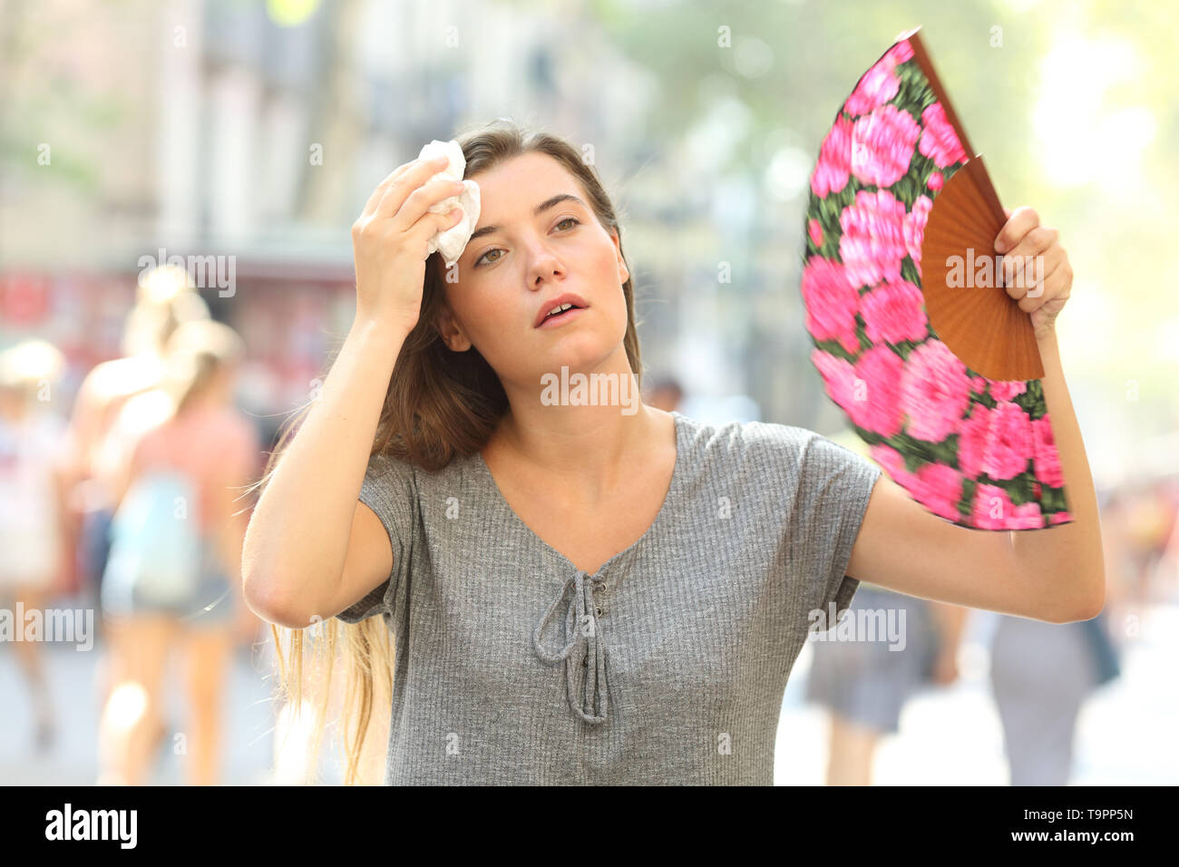 Front view portrait of a overwhelmed girl complaining suffering heat stroke in the street on summer Stock Photo