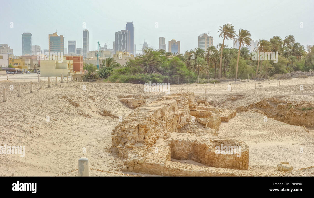 Archaeological excavations of an old fort and Manama skyline in the background, Qal'at al-Bahrain Stock Photo