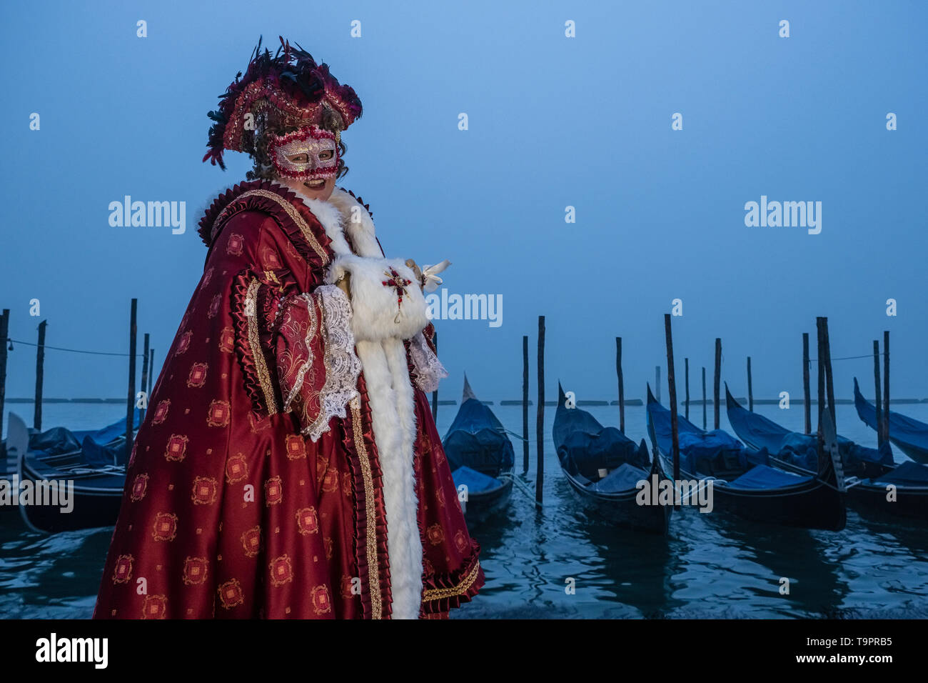 Portrait of a feminin masked person in a beautiful creative costume, posing at Grand Canal, Canal Grande, celebrating the Venetian Carnival Stock Photo