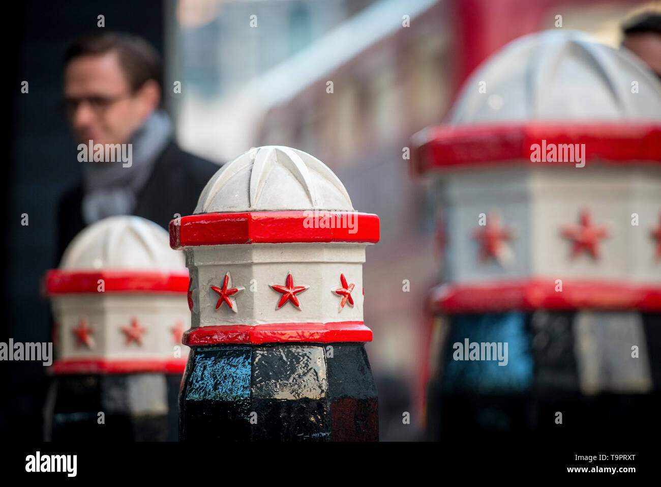 The iconic red white and black iron City of London bollards and a city worker commuter on his way to the office Stock Photo
