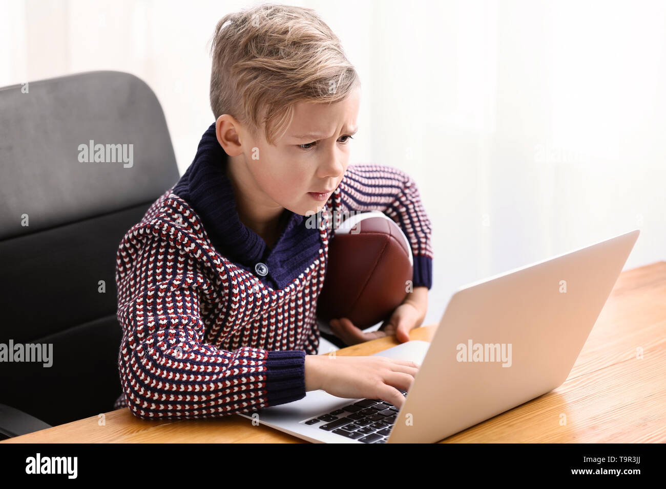 Cute boy playing video game on laptop at home Stock Photo - Alamy