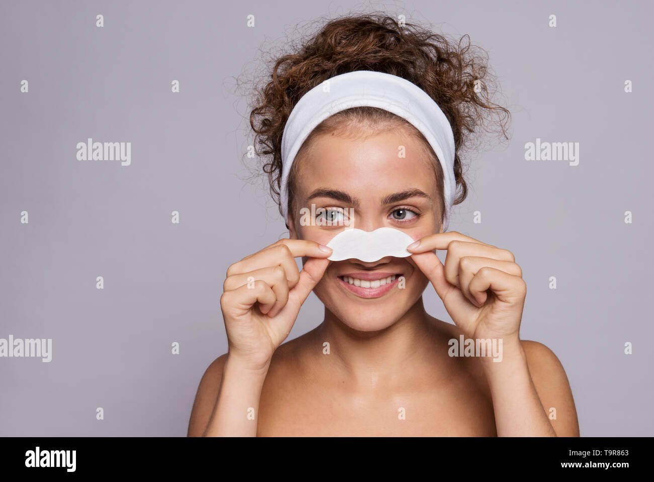 Portrait of a young woman cleaning face in a studio, beauty and skin care. Stock Photo
