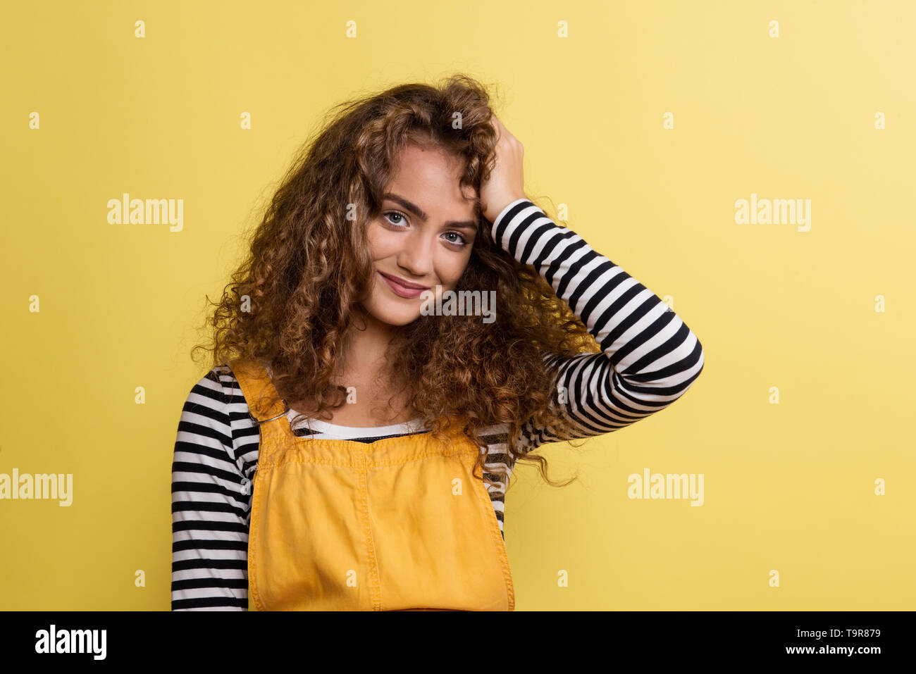 Portrait of a young woman in a studio on a yellow background. Stock Photo