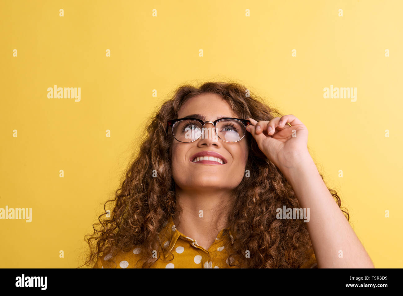 Portrait of a young woman with glasses in a studio on a yellow background. Stock Photo