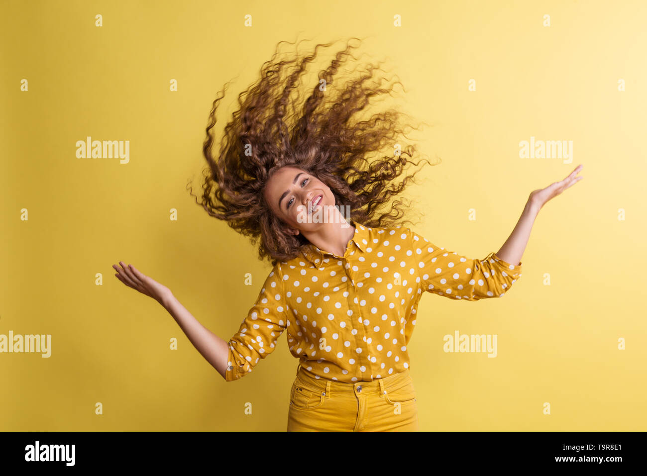 Portrait of a young woman in a studio on a yellow background, having fun. Stock Photo