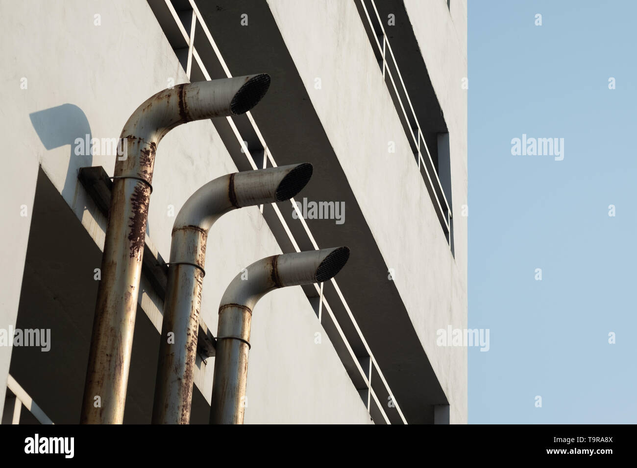 Three pipe ventilation ducts For venting smoke outside the building, rusty surface surrounding with sunlight and blue sky background. Stock Photo