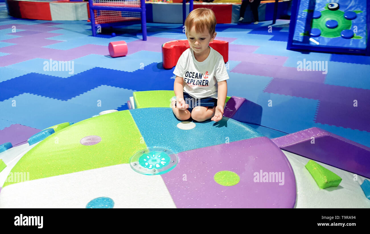 Portrait Of Smiling Little Boy Sitting On The Colorful Children