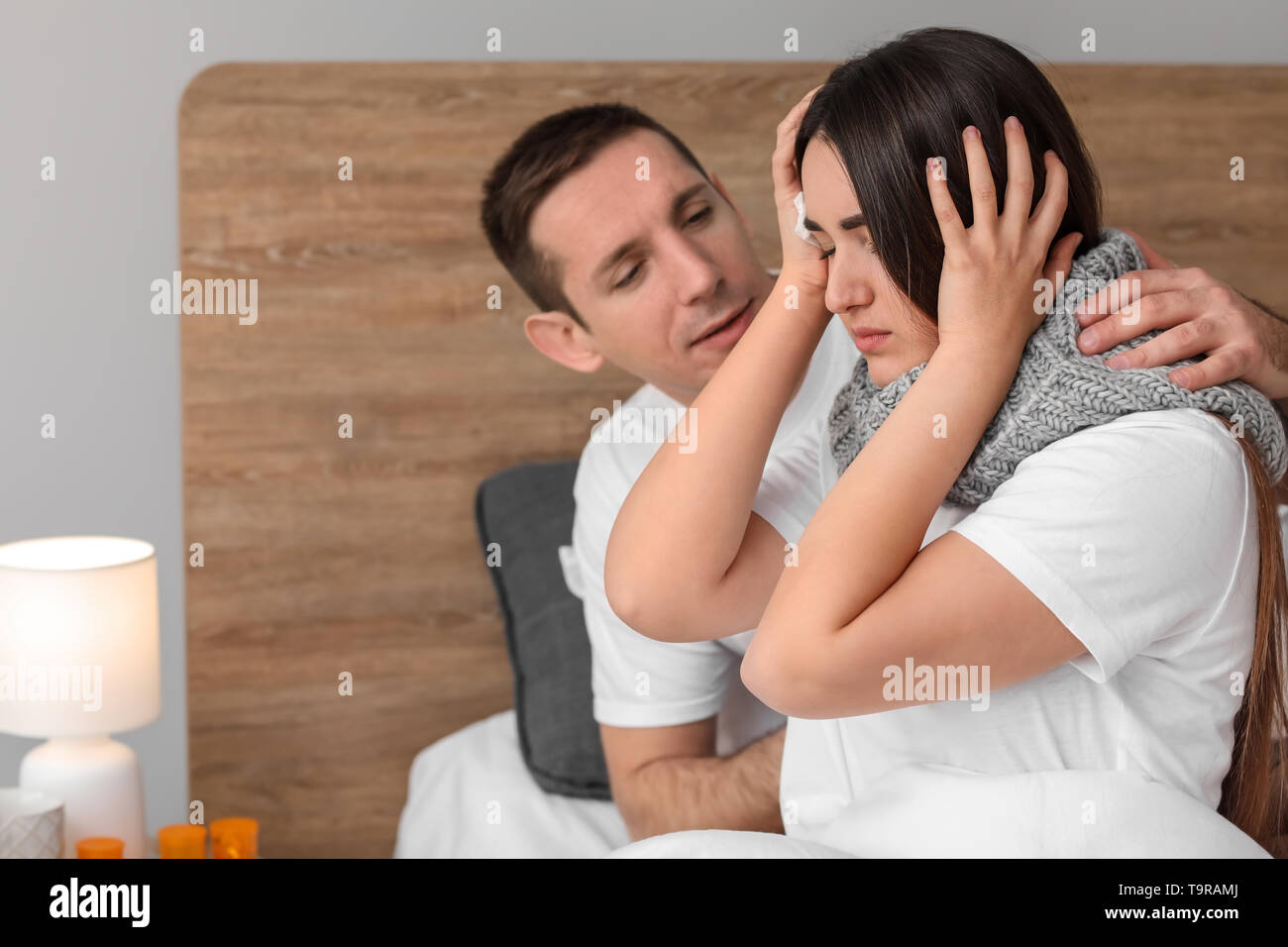 Man taking care of his wife ill with flu at home Stock Photo