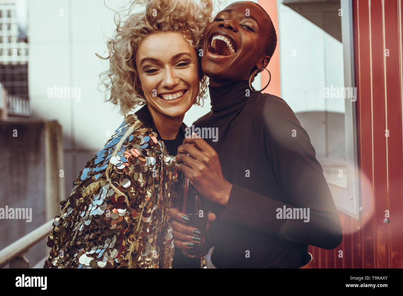 Two caucasian and african woman friends standing together and laughing. Female friends enjoying their weekend with fun. Stock Photo