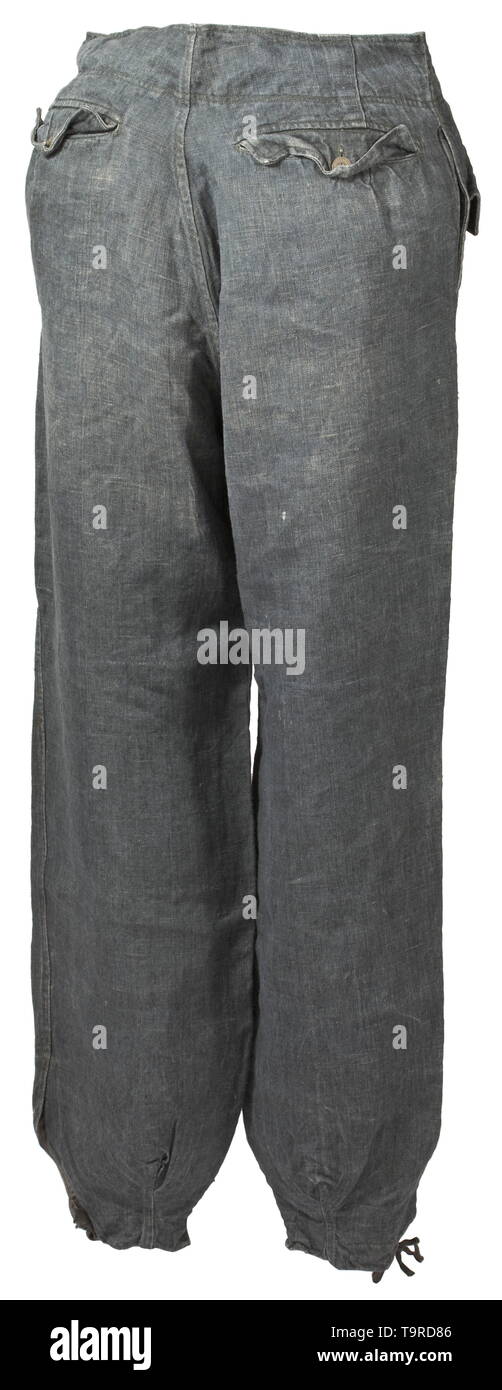 A pair of trousers to the fatigue outfit for tank- or assault gun crews depot piece Broad-cut trousers of field-grey drill cloth with covered fly and sheet metal or cardboard buttons. The two front pockets of unequal sizes and integrated at different angles, superimposed pocket on the left upper thigh, integrated straight hip pockets, each with closure flap and a single button, leg closure with overfall. Brownish imitation silk liner. The web belt missing, signs of usage and small blemishes. A very rare special clothing issue. historic, historical, 20th century, Editorial-Use-Only Stock Photo