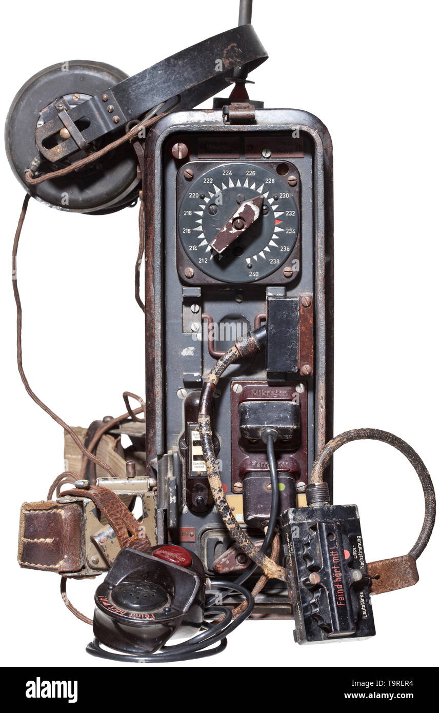 A field radio set 'Feldfu.b2' Dark-grey painted Bakelite housing, lateral imprint 'Bodenständig'. Removable apparatus lid, the outside with phonetic spelling chart, the inside with rivet affixed operating instructions. Hinged cover for technical accessories, the inside with rivet affixed contents plate, interior battery compartment with connector cable and strap, webbed belt for carrying support. Web grip and appending hook for carry apparatus. Control panel with name plate 'Feldfu. b2, 016193, 44', indicator labels, switches and all bushings. Included is a foldable rod ant, Editorial-Use-Only Stock Photo