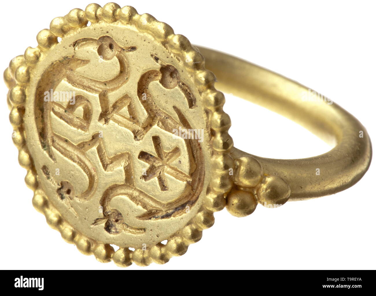 An Alemannic gold ring with religious symbols, 2nd half of 7th century Solid, circa 3 mm wide shank, forked, hammered down and soldered together under the seal face. Each shoulder set with three gold globules. Seal face also surrounded by a solid wire of pearls. Engraved into the surface are religious symbols: alpha and omega, chi and rho in unusual typography give evidence of a Christian background. The letters are connected by curved lines terminating in animal heads, which can be interpreted ambivalently as Christian or heathen symbols. A ring, Additional-Rights-Clearance-Info-Not-Available Stock Photo