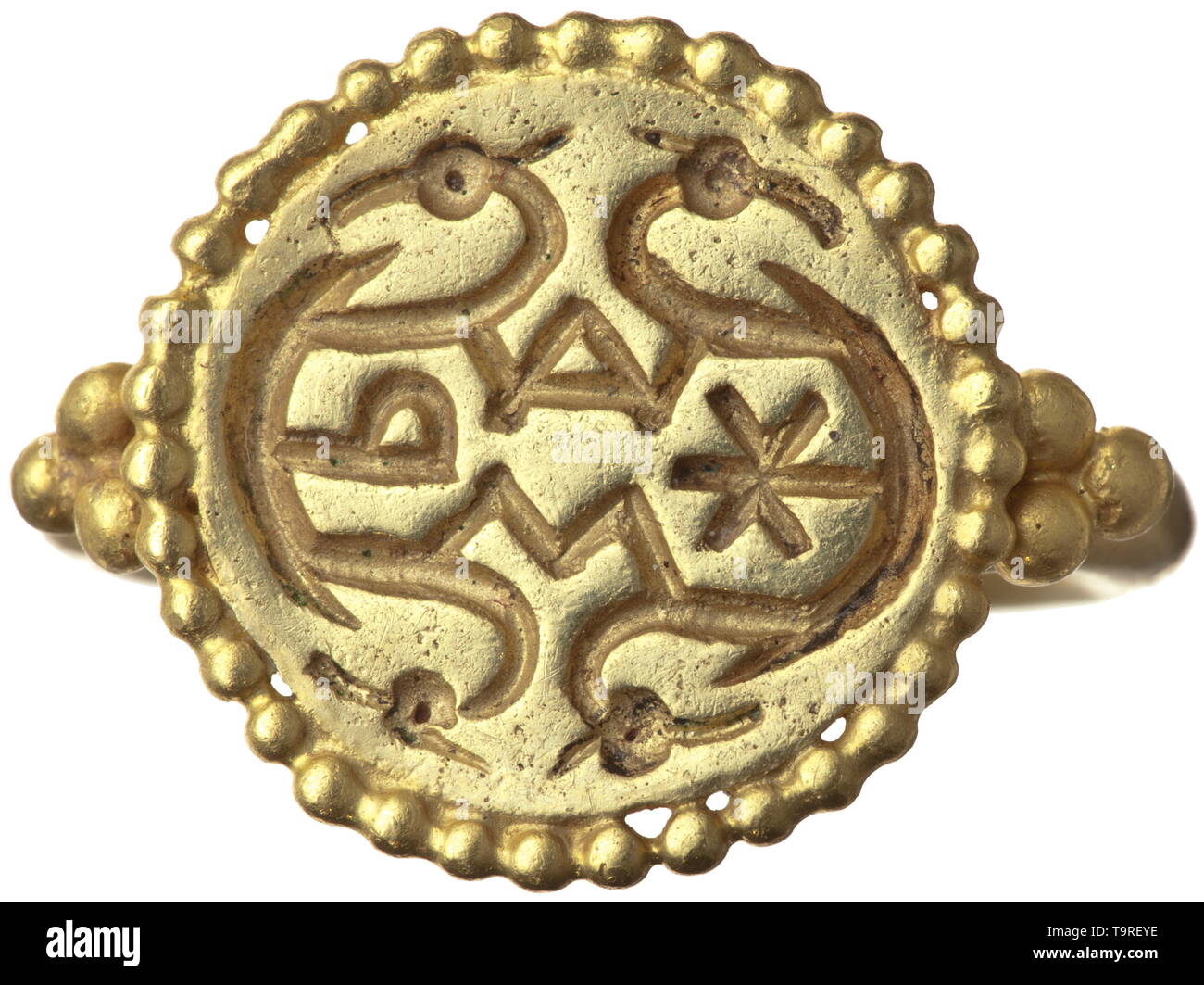 An Alemannic gold ring with religious symbols, 2nd half of 7th century Solid, circa 3 mm wide shank, forked, hammered down and soldered together under the seal face. Each shoulder set with three gold globules. Seal face also surrounded by a solid wire of pearls. Engraved into the surface are religious symbols: alpha and omega, chi and rho in unusual typography give evidence of a Christian background. The letters are connected by curved lines terminating in animal heads, which can be interpreted ambivalently as Christian or heathen symbols. A ring, Additional-Rights-Clearance-Info-Not-Available Stock Photo