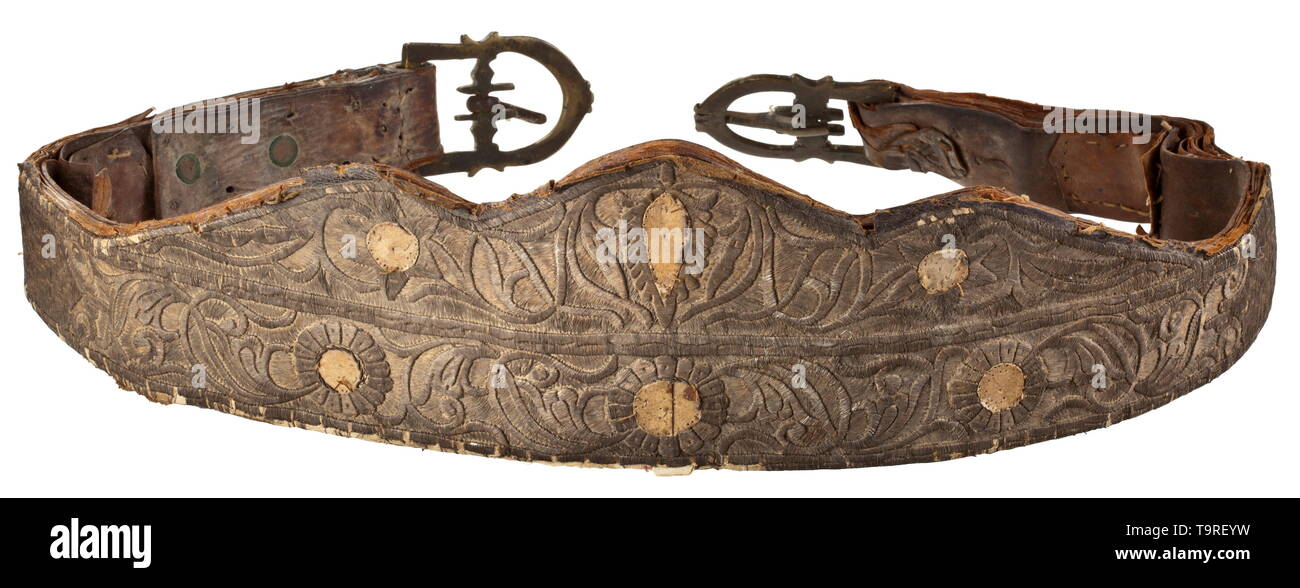 A silver-embroidered North African splendid saddle, 19th century Leather and fur covered wood construction. The leather blanket with raised ornamental embroidery made of silver tinsel cord (over applied cardboard pieces). Including the en suite decorated head harness and tackle with attached buckles and a pair of brass stirrups engraved on the exterior. Silver embroidery darkened and rubbed in the thigh area. A finely crafted saddle clearly improvable through cleaning. Length circa 67 cm. historic, historical, Africa, African, weapon, arms, weapo, Additional-Rights-Clearance-Info-Not-Available Stock Photo