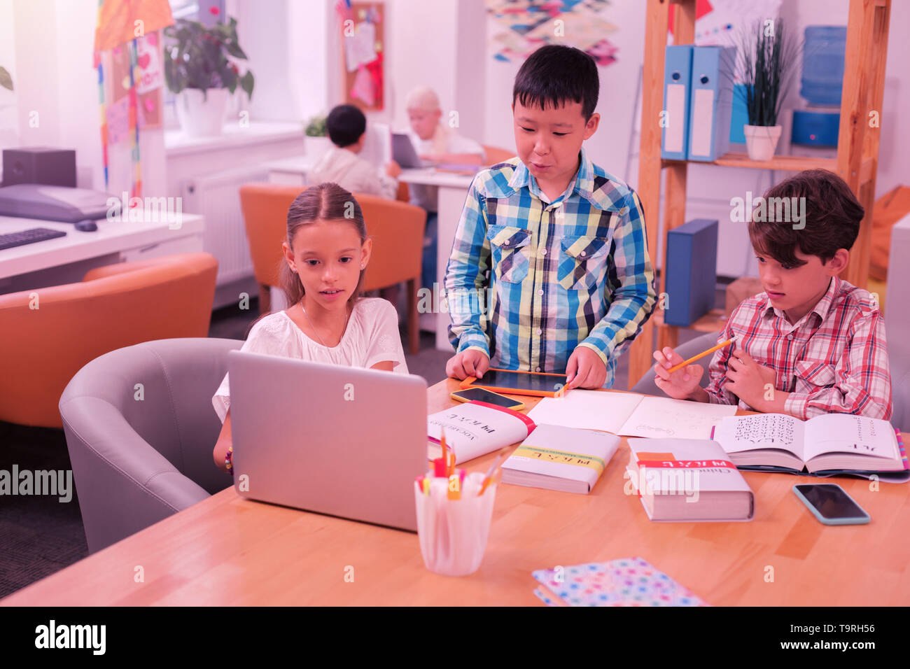 Children using modern technologies doing their homework. Stock Photo