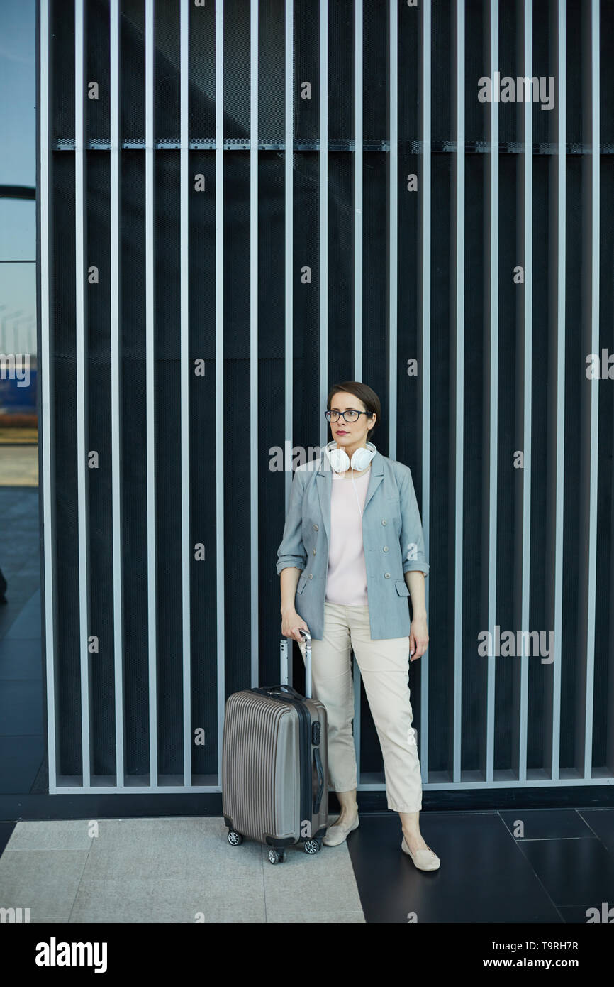 Attractive business lady with wheeled suitcase Stock Photo